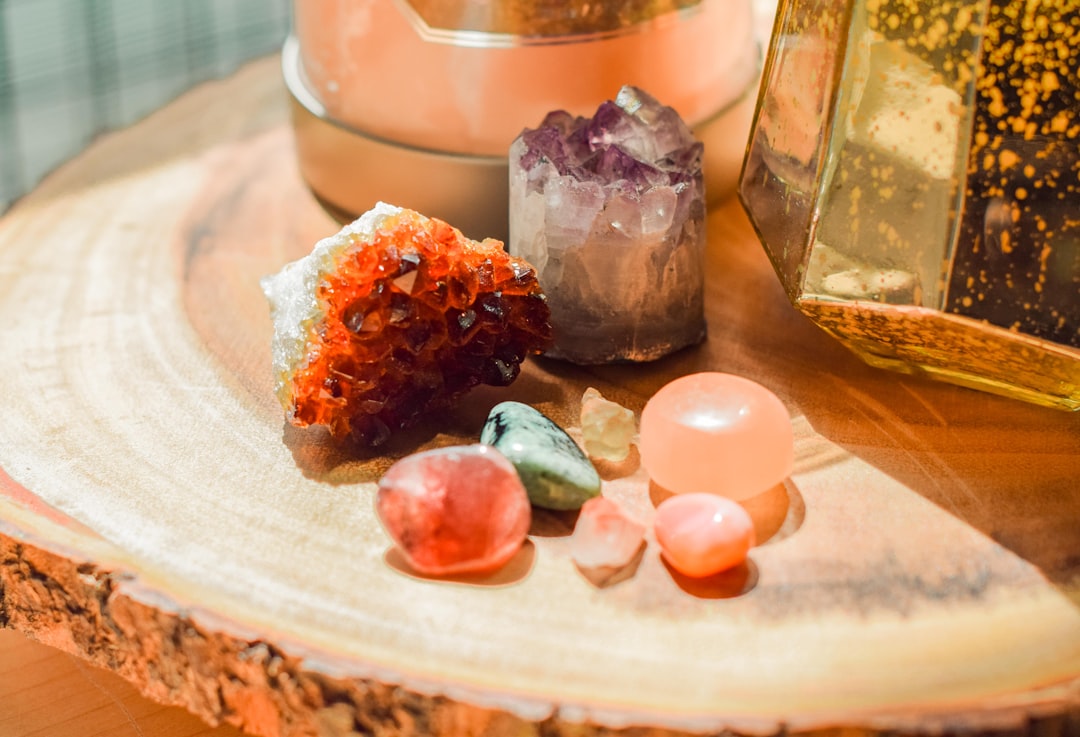A serene setup featuring various colorful crystals arranged on a natural surface, with a small bowl of water and sage for cleansing.